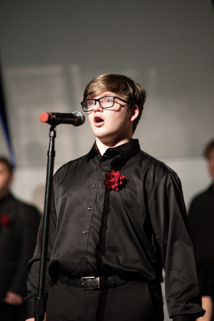 Noah Varland (11) steps up to sing at the microphone. Varland said, "I think the concert ran very smoothly, it was a great first concert." 